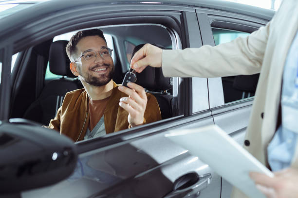 Happy customer collecting her car, shaking hands with a salesperson